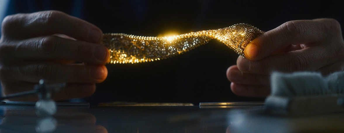 A visual of hands holding a bracelet with a golden glow