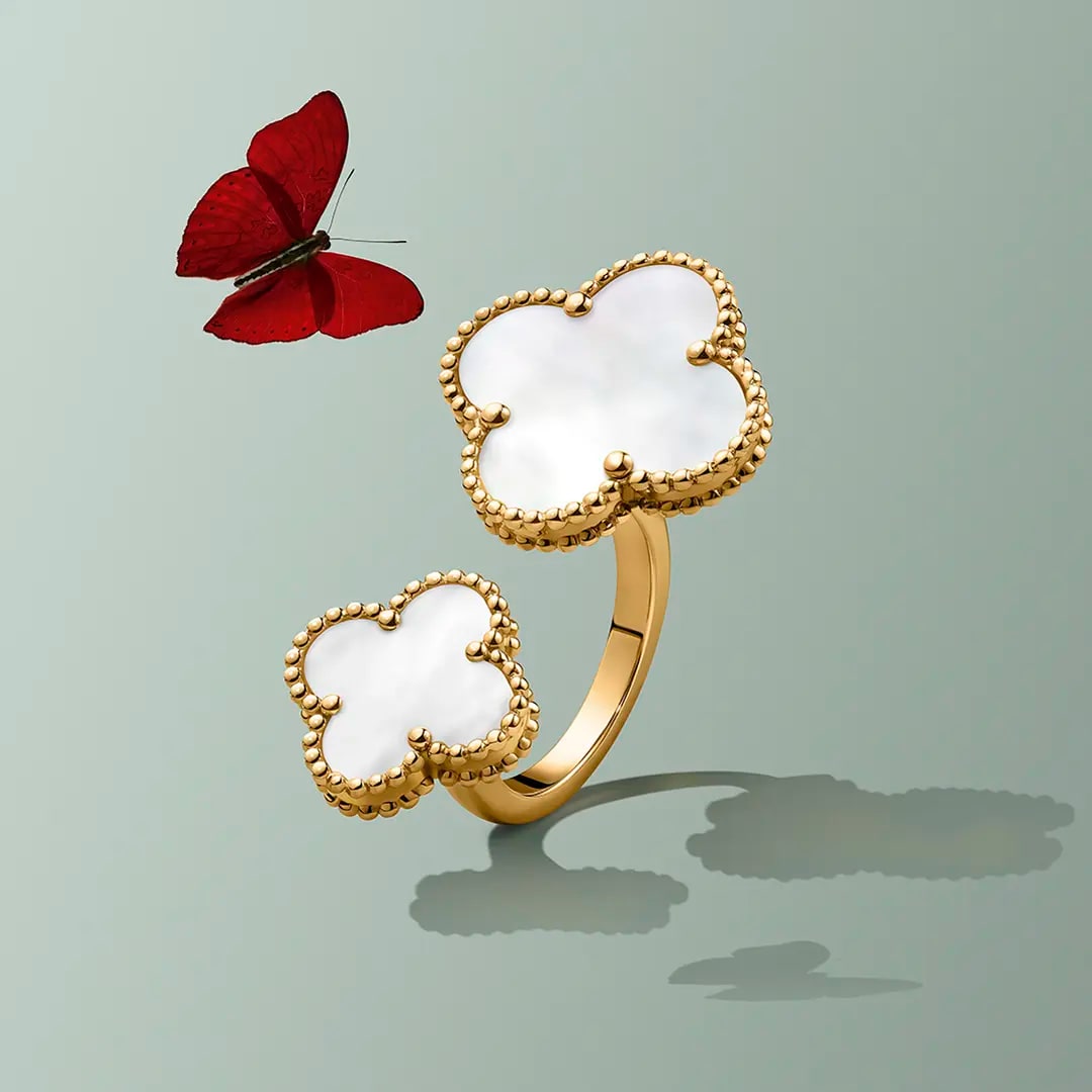White Alhambra ring with a red butterfly flying on the left on  a light green background