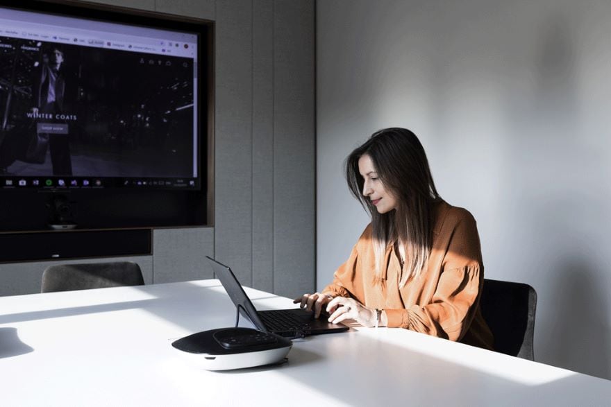 A woman typing on a computer in a conference room