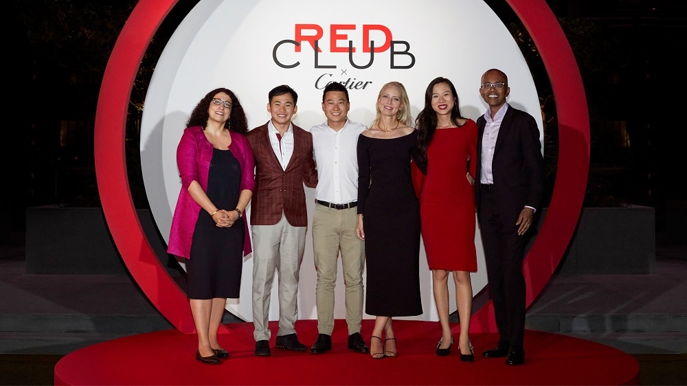 Six people posing under Red Club X Cartier sign
