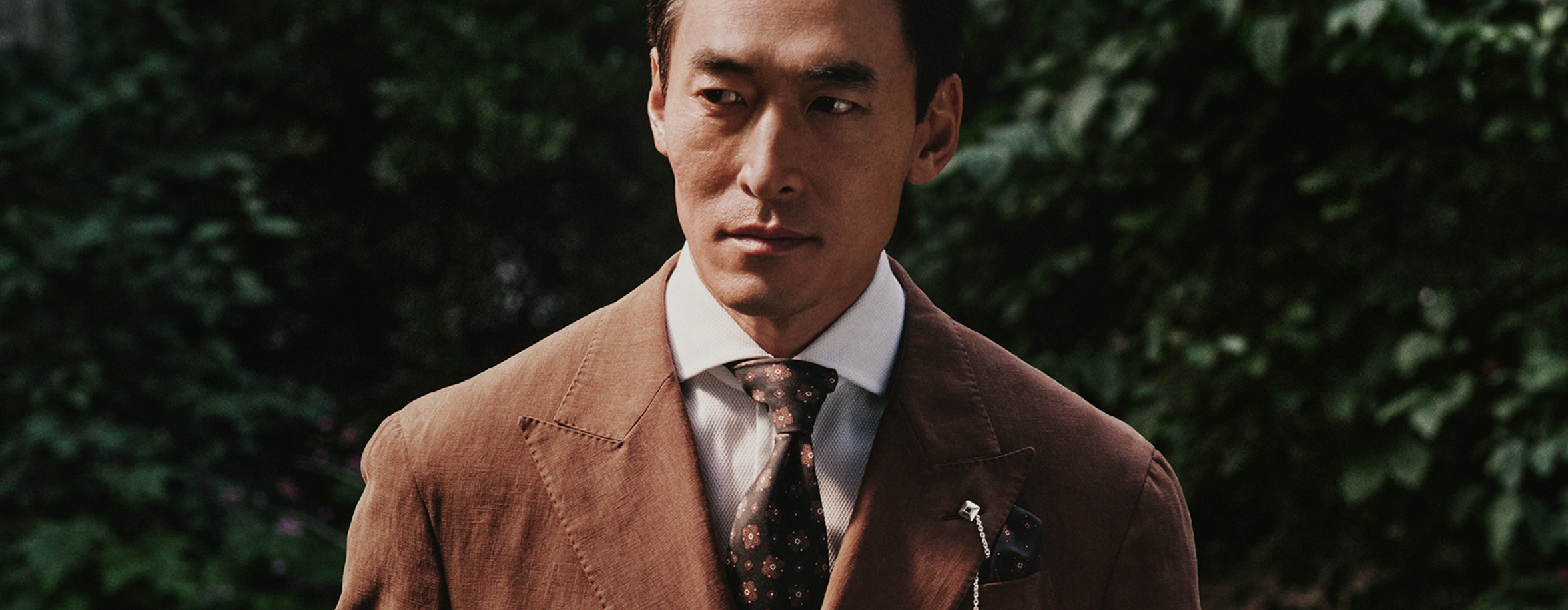 Men pausing with a light brown suite white shirt and brown tie