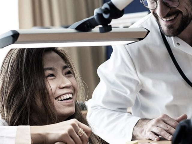 Two watchmakers smiling while working at a desk