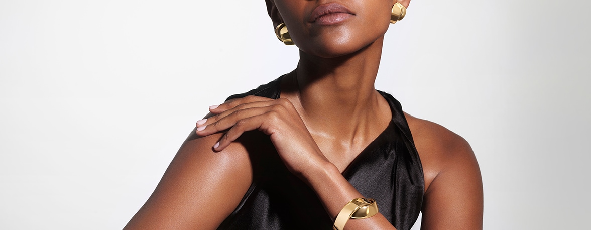 Model pausing with gold earrings and watch