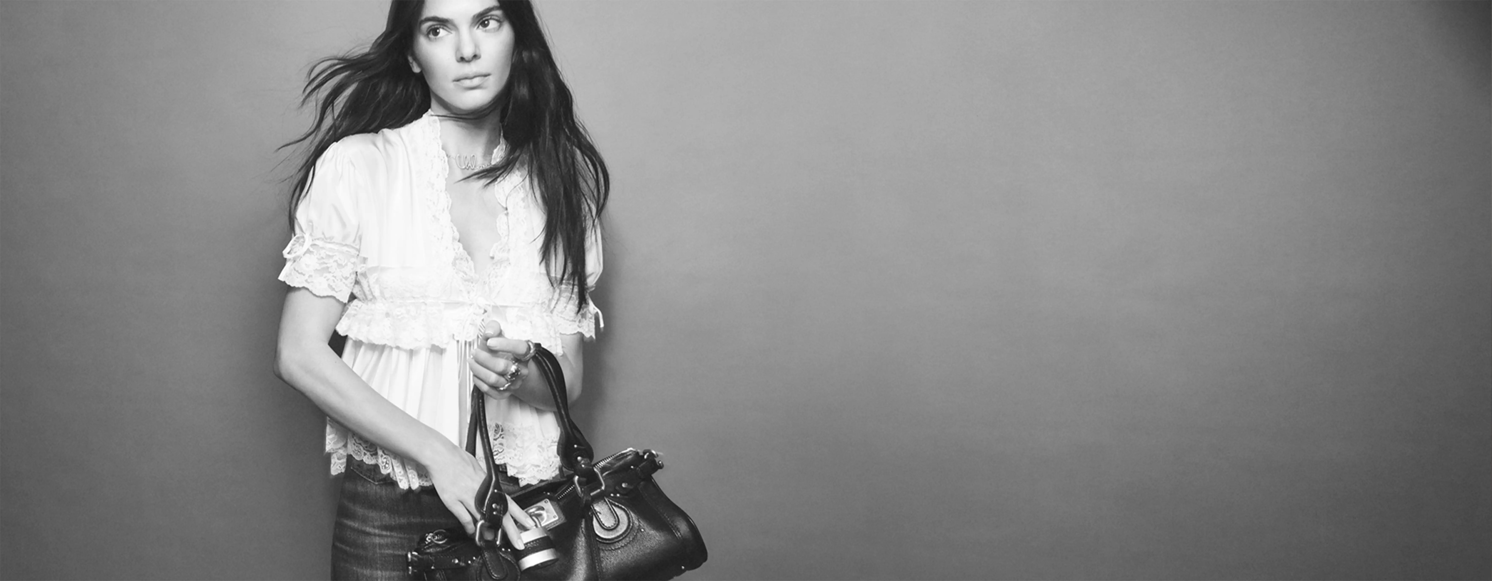 A stylish black and white portrait of a woman carrying Chloé black leather handbag, showcasing a casual yet elegant look.