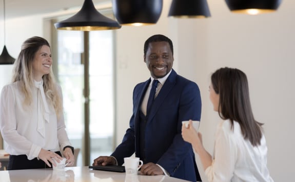 A diverse group of workers having a conversation and smiling in the conference room