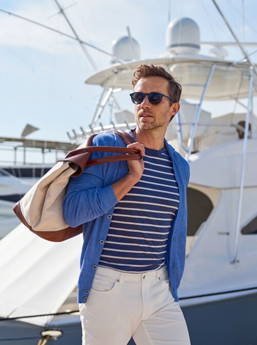 Male model holding a bag with a boat in the background-Peter Millar-Richemont Group