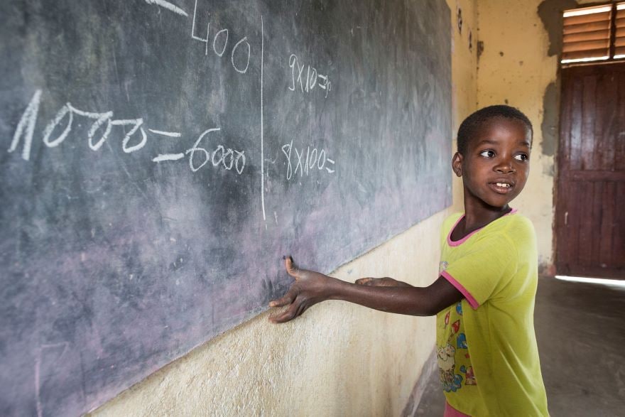 A young boy writing on a blackboard in a school room in Mosambique