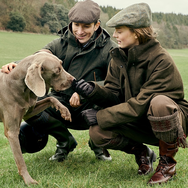 2 people in the countryside playing with a dog
